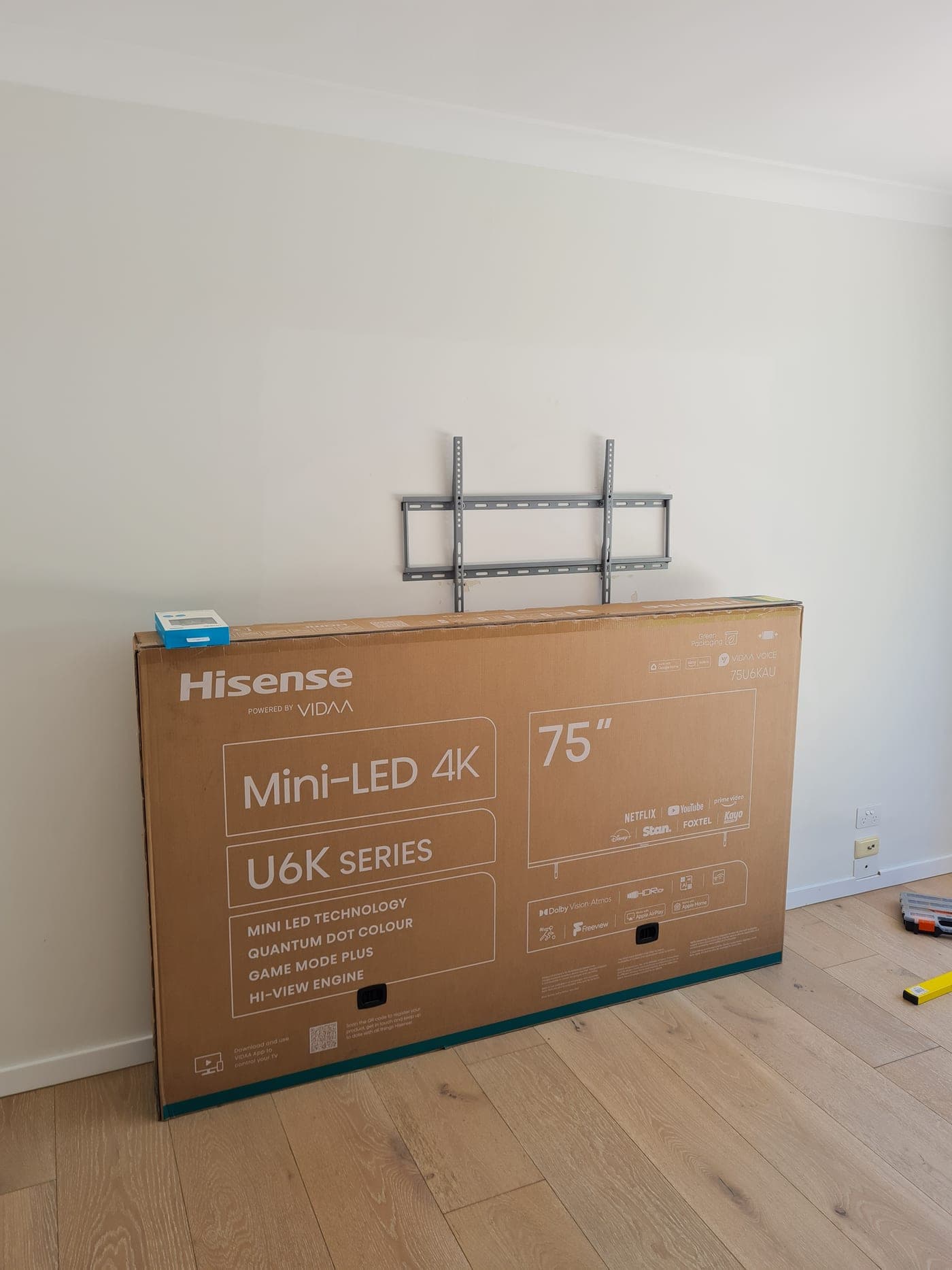 Wall bracket up and a boxed 75-inch TV ready to hang