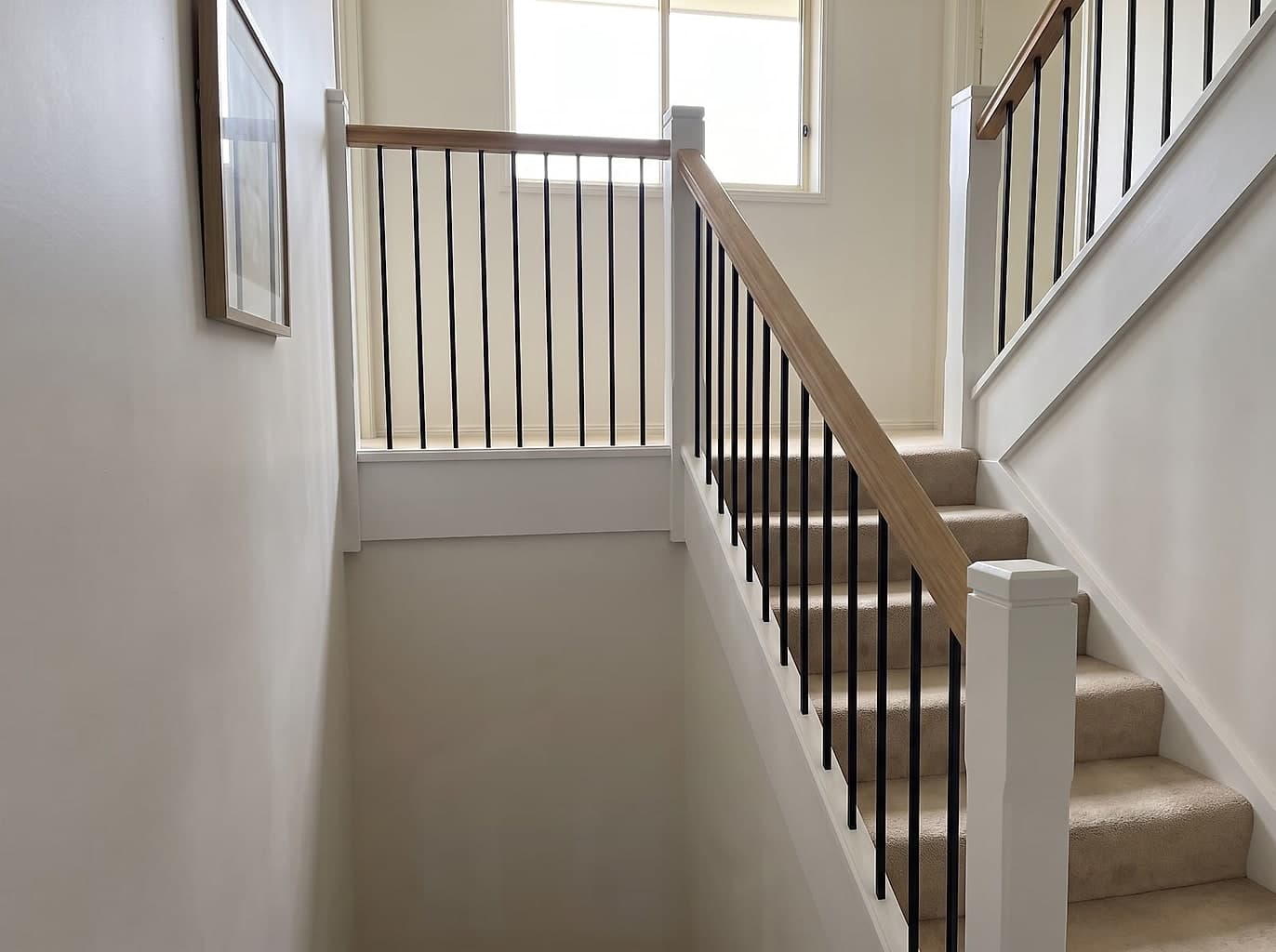 The same staircase with a new oak handrail and slim black steel rods, properly spaced and solid