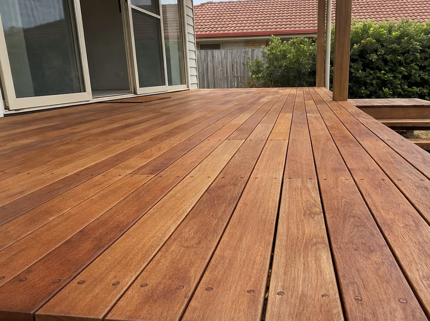 The same deck with the split and broken boards replaced, the whole surface sanded back to warm honey timber and finished with a satin oil