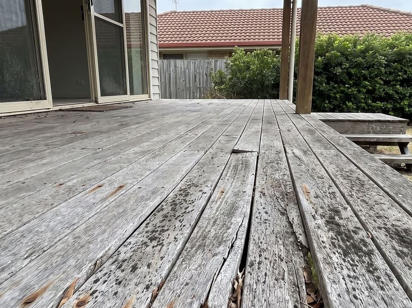 Timber deck gone silver-grey with lichen, raised grain and split boards