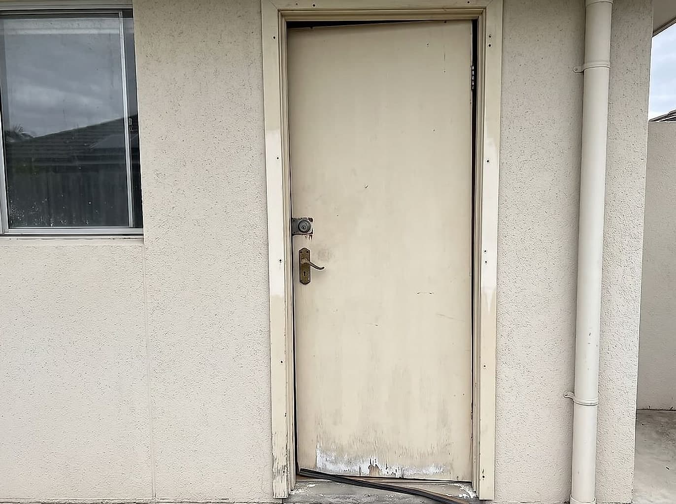 Tired back doorway with the security door taken off, the timber door hanging crooked and the seal perished