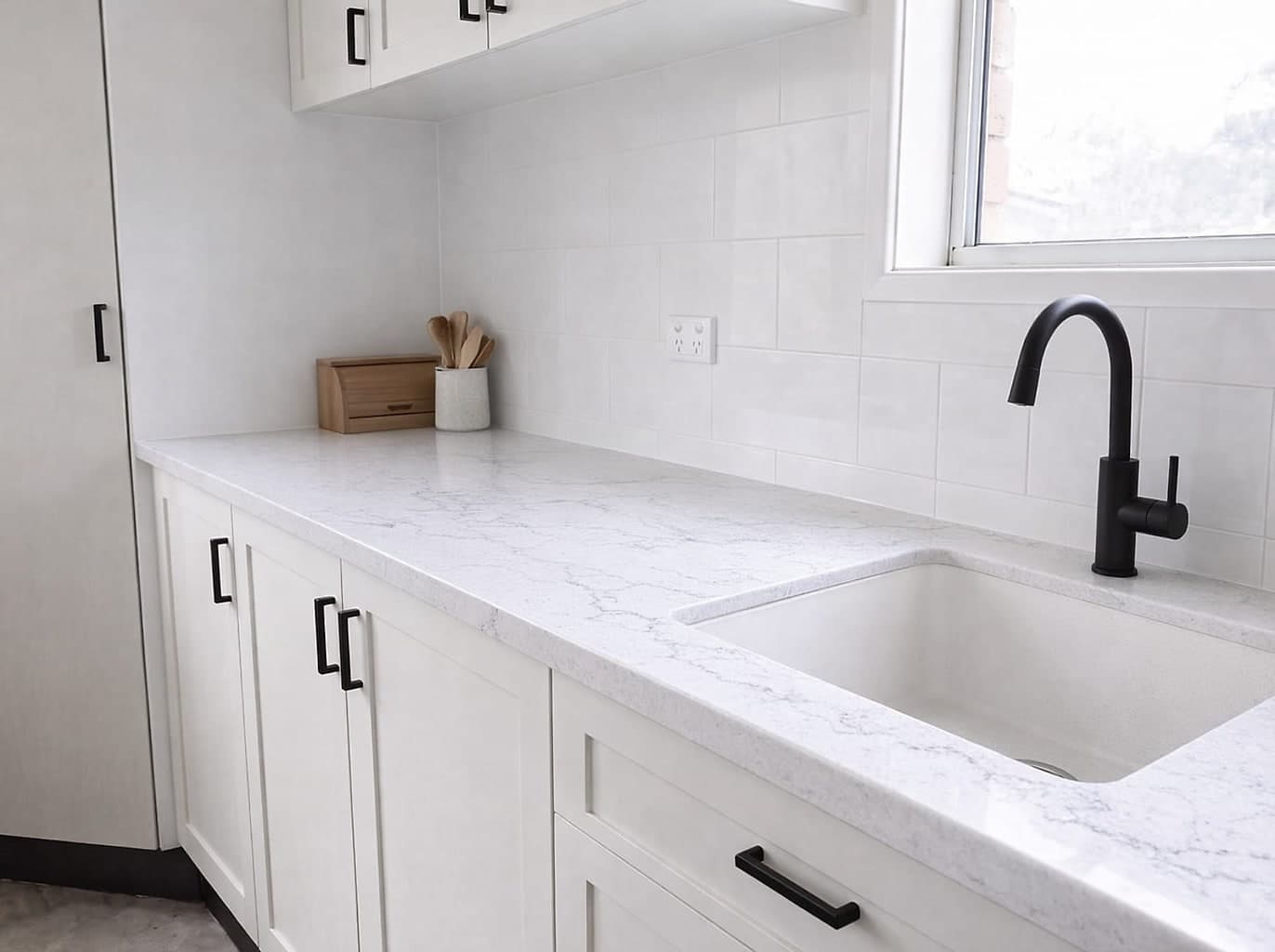 The same run with a pale stone benchtop, large white tiles and resprayed cupboard doors
