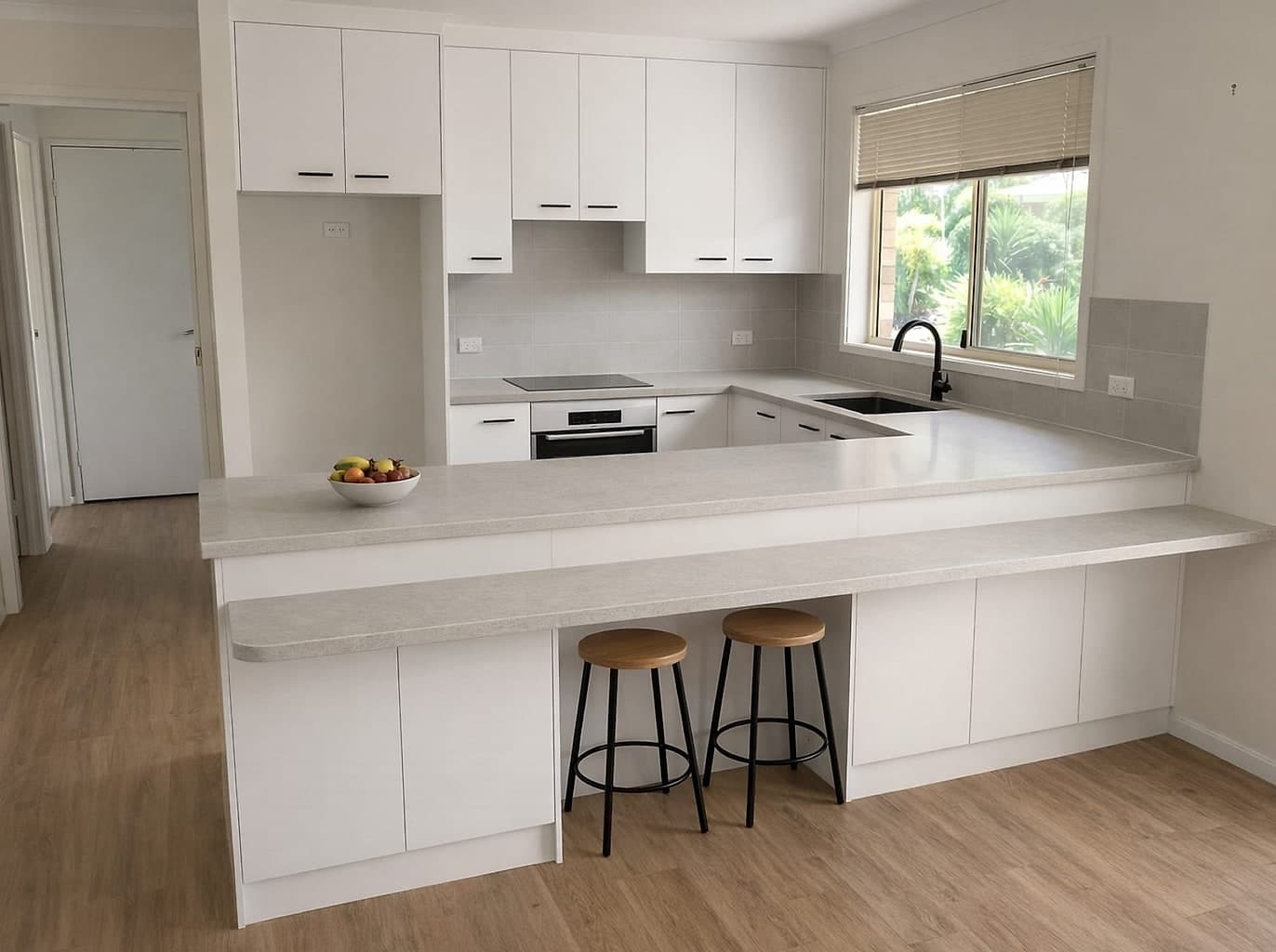 The same kitchen with a stone benchtop, an integrated dishwasher and the peninsula given an overhang for stools