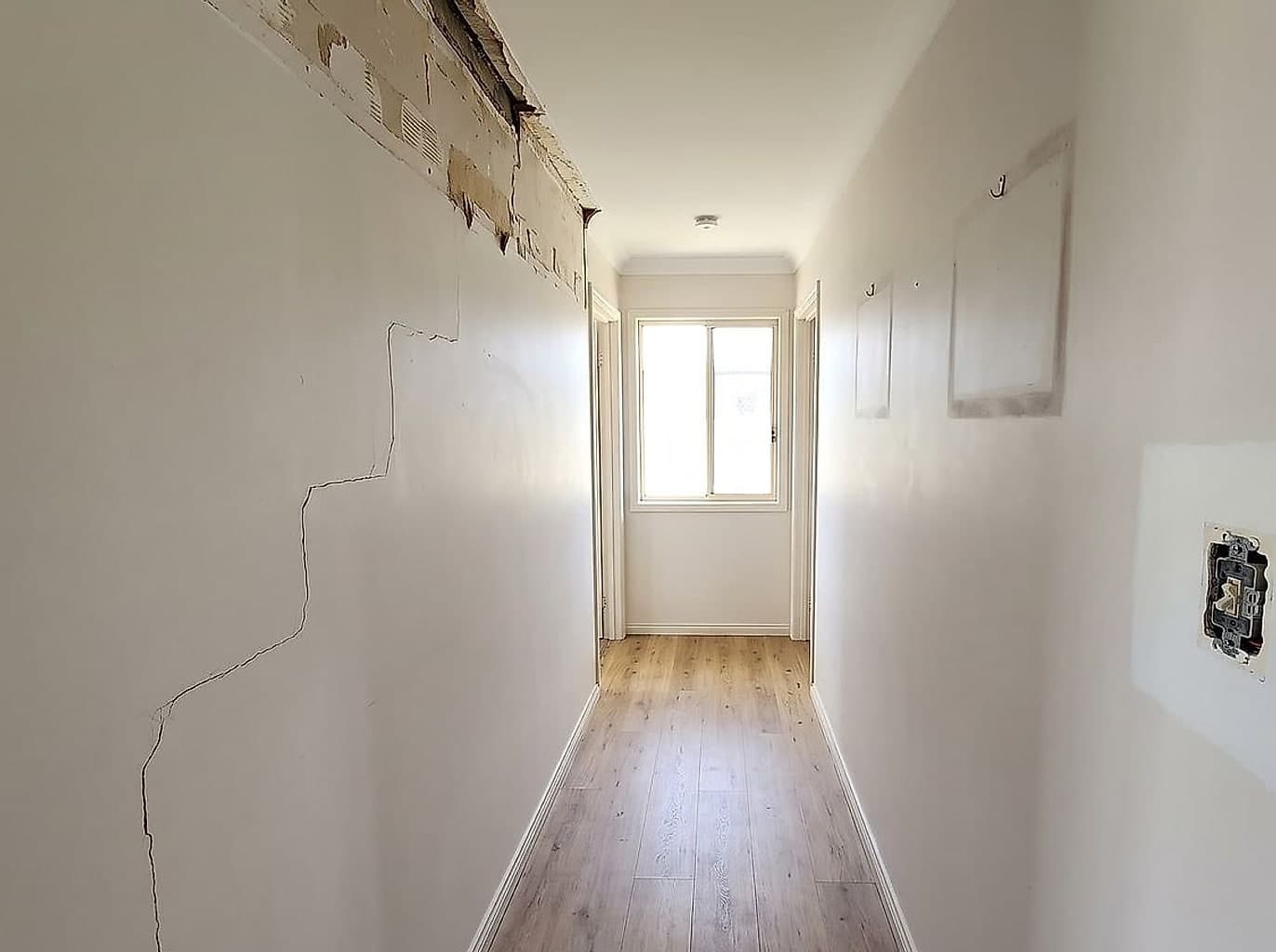 Hallway with a run of cornice taken down and a crack stepping down the wall