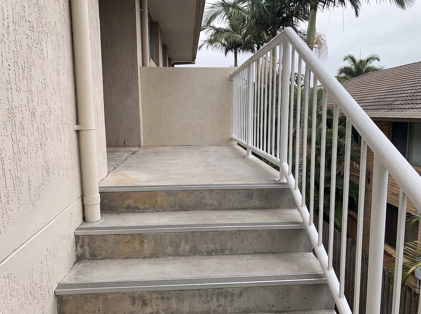 The same stairwell with a new galvanised balustrade, rebuilt nosings with non-slip strips and patched render